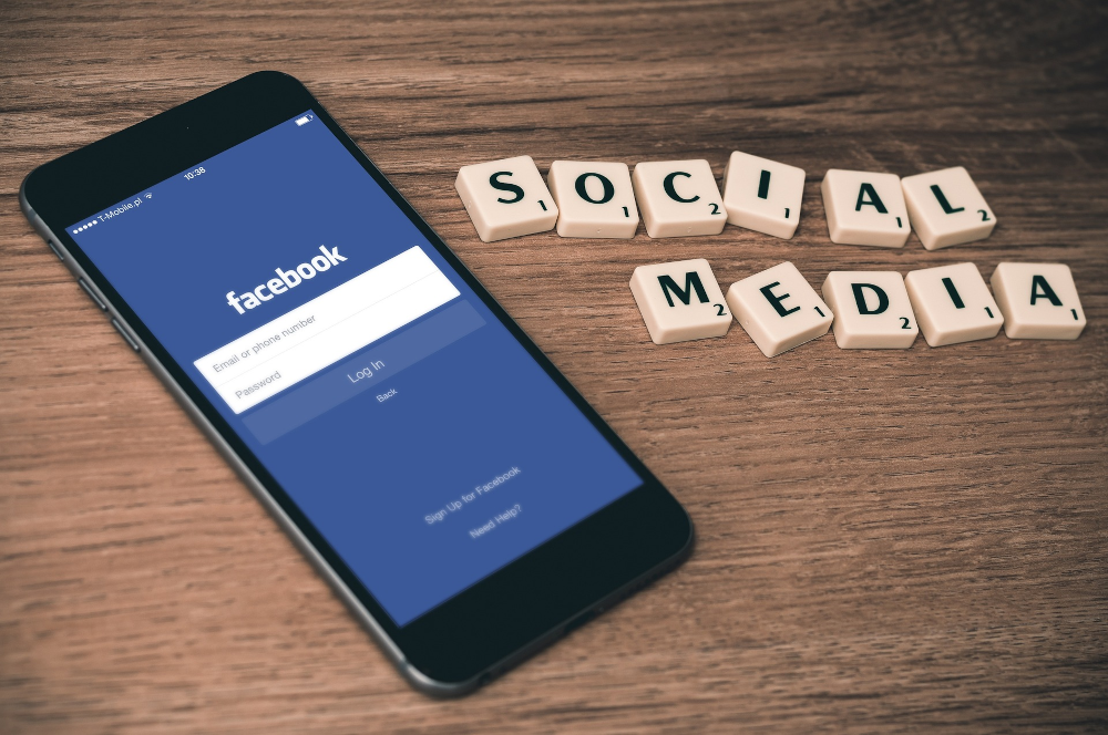 Un smartphone avec la page de connexion à Facebook ouvere et des lettres de Scrabble qui forment le mot Social Media